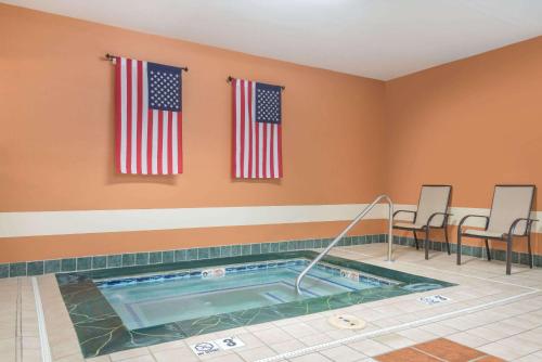 a hot tub in a room with two american flags at Ramada by Wyndham Catlettsburg Ashland in Catlettsburg