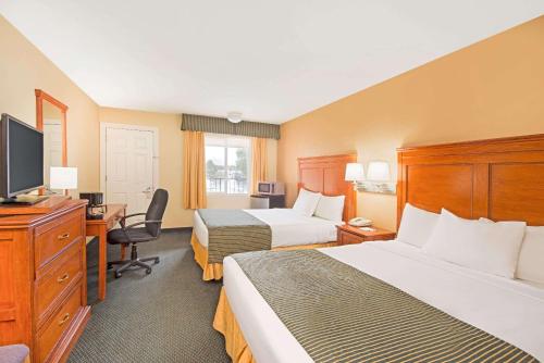 a hotel room with two beds and a flat screen tv at Ramada by Wyndham Flagstaff East in Flagstaff