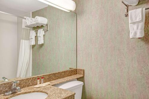 a bathroom with a sink and a toilet and a mirror at Ramada by Wyndham Parsippany in Parsippany
