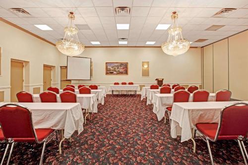 a conference room with white tables and red chairs at Ramada by Wyndham Flemington in Flemington