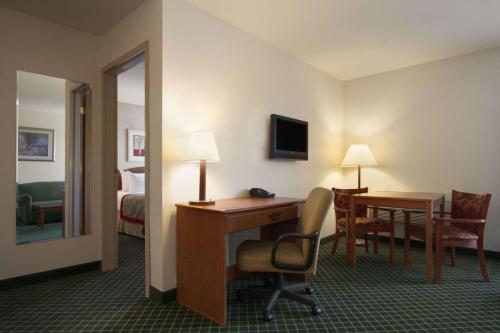 a hotel room with a desk and a bedroom at Ramada by Wyndham SeaTac Airport in SeaTac