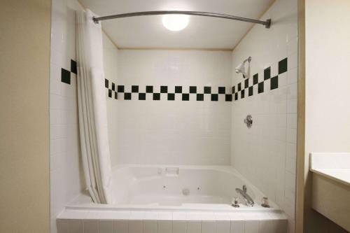 a white bath tub in a bathroom with a sink at Ramada by Wyndham SeaTac Airport in SeaTac