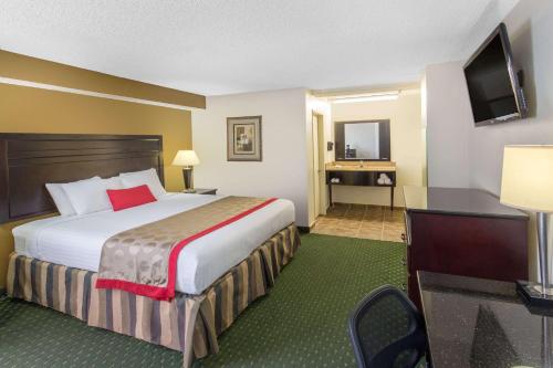 a hotel room with a bed and a flat screen tv at Ramada by Wyndham Ontario Airport & Convention Center in Ontario