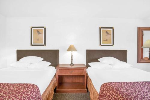 a hotel room with two beds and two lamps at Ramada by Wyndham Barstow in Barstow