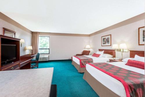 a hotel room with two beds and a flat screen tv at Ramada by Wyndham Strasburg Dover in Strasburg