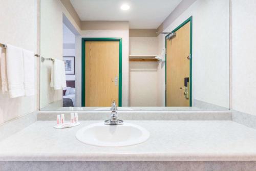 a bathroom with a sink and a large mirror at Ramada by Wyndham Strasburg Dover in Strasburg