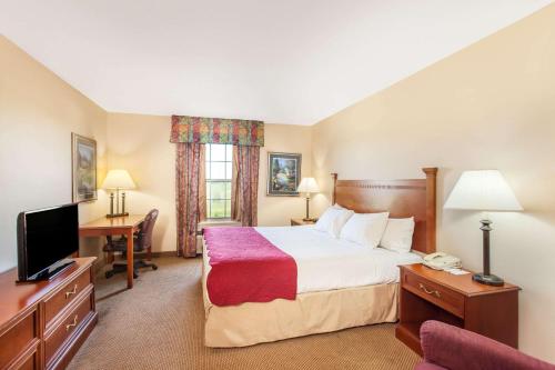 a hotel room with a bed and a desk at Ramada by Wyndham Sparta/At Speedway in Sparta