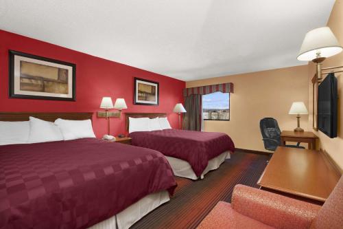 two beds in a hotel room with red walls at Ramada by Wyndham East Orange in East Orange