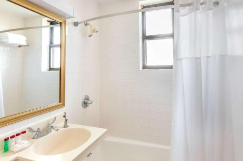 ein weißes Badezimmer mit einem Waschbecken und einem Spiegel in der Unterkunft Ramada by Wyndham Jersey City in Jersey City