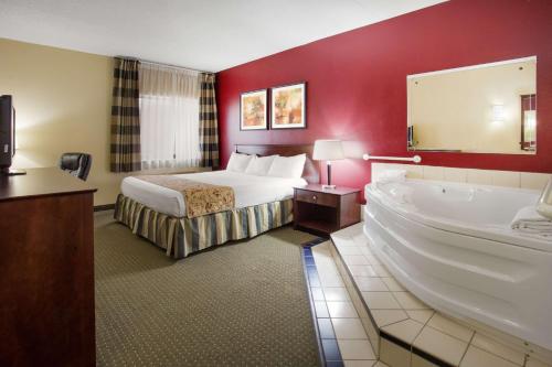 a hotel room with a bed and a bath tub at Ramada by Wyndham Bettendorf in Bettendorf