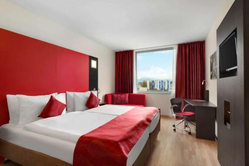 a hotel room with a bed and a desk and a window at Ramada Encore by Wyndham Geneva in Geneva