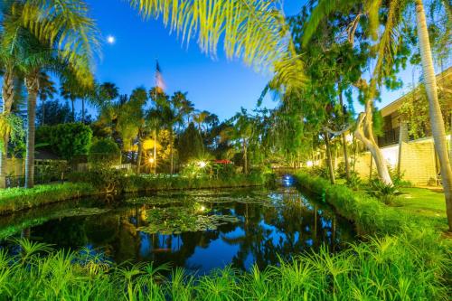 a pond in front of a building with palm trees at Ramada by Wyndham Santa Barbara in Santa Barbara