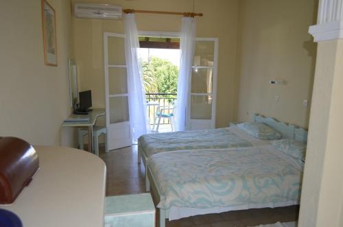 a bedroom with a bed and a door to a balcony at The Mayflower Studios & Apartments in Moraitika