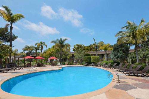 a swimming pool at a resort with chairs and palm trees at Ramada by Wyndham Santa Barbara in Santa Barbara