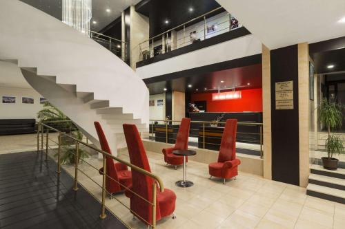 a lobby with red chairs and a staircase at Ramada Iasi City Center in Iaşi