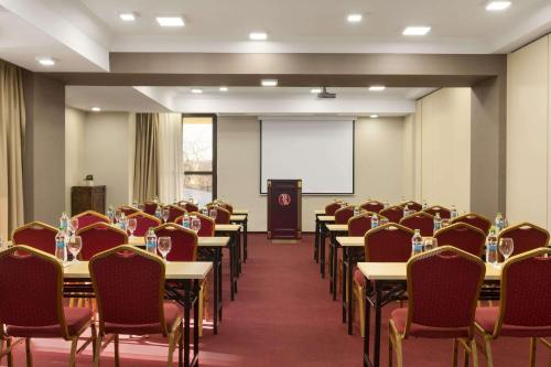 a conference room with tables and chairs and a podium at Ramada Iasi City Center in Iaşi