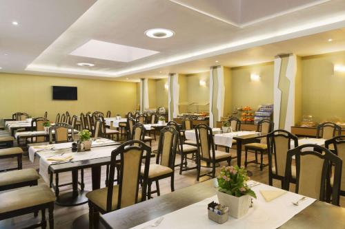 a restaurant with tables and chairs in a room at Ramada Iasi City Center in Iaşi