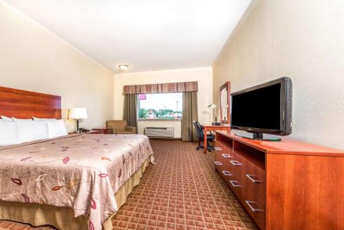 a hotel room with a bed and a flat screen tv at Ramada by Wyndham College Station in College Station