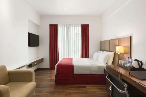 a hotel room with a bed and a couch at Ramada Encore Domlur Bangalore in Bengaluru