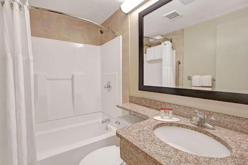 a bathroom with a sink and a toilet and a mirror at Ramada by Wyndham Staten Island in Staten Island