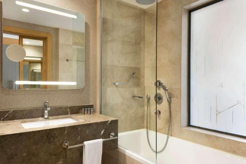 a bathroom with a shower and a sink and a mirror at Ramada Hotel & Suites by Wyndham Adana in Adana