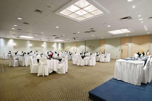 a room full of tables with white tablesearcher at Ramada by Wyndham Trenton in Trenton