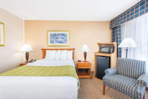 Pokój hotelowy z łóżkiem i krzesłem w obiekcie Ramada by Wyndham Cumberland Downtown w mieście Cumberland
