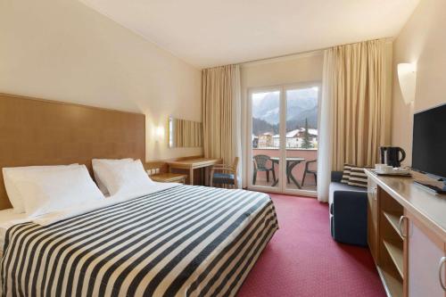 ein Hotelzimmer mit einem Bett und einem Balkon in der Unterkunft Ramada Hotel & Suites Kranjska Gora in Kranjska Gora