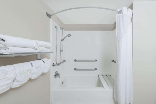 a white bathroom with a shower and towels at Hotel AVA Laredo in Laredo