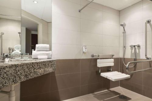ein Bad mit einem Waschbecken und einer Dusche in der Unterkunft Hotel Ramada Graz in Premstätten