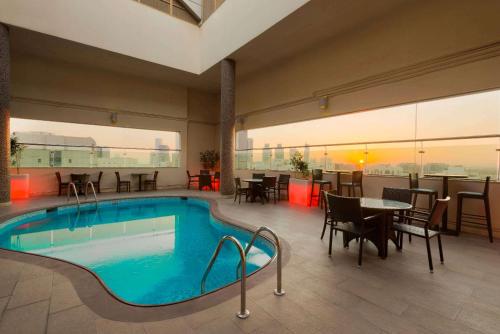 a pool in a hotel room with tables and chairs at Ramada Downtown Abu Dhabi in Abu Dhabi