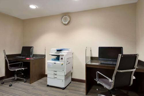 an office with two desks and a computer on a wall at Ramada Downtown Abu Dhabi in Abu Dhabi