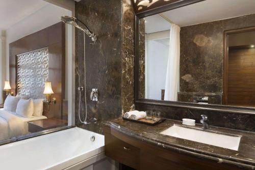 a bathroom with a tub and a sink and a bed at Ramada Plaza By Wyndham, Chandigarh Zirakpur in Chandīgarh
