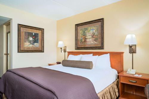 a hotel room with a bed and two pictures on the wall at Ramada by Wyndham Plymouth Hotel & Conference Center in Plymouth