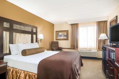 a hotel room with a bed and a flat screen tv at Ramada by Wyndham Plymouth Hotel & Conference Center in Plymouth