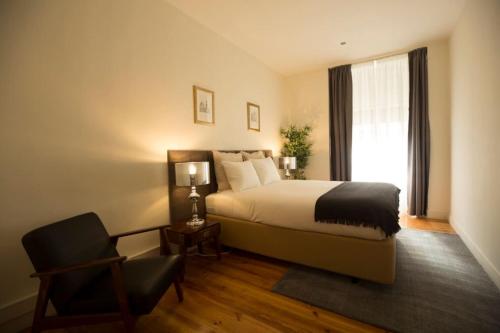 a bedroom with a bed and a chair and a window at Ola Lisbon - Chiado IV in Lisbon