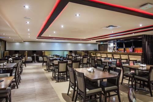 a restaurant with tables and chairs and a bar at Ramada by Wyndham Jackson's Point in Georgina