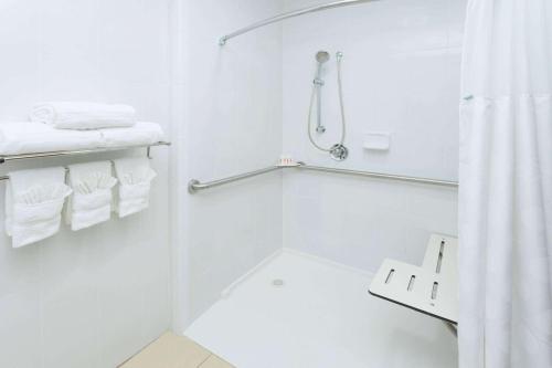 a white bathroom with a shower and white towels at Ramada Plaza by Wyndham Chicago North Shore in Wheeling