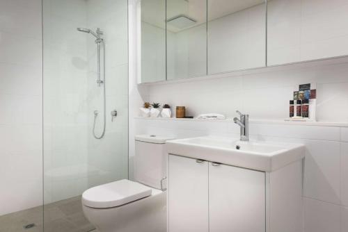a white bathroom with a toilet and a sink at Ramada by Wyndham VetroBlu Scarborough Beach in Perth