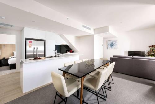 a dining room with a black table and white chairs at Ramada by Wyndham VetroBlu Scarborough Beach in Perth