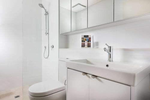 a white bathroom with a sink and a shower at Ramada by Wyndham VetroBlu Scarborough Beach in Perth
