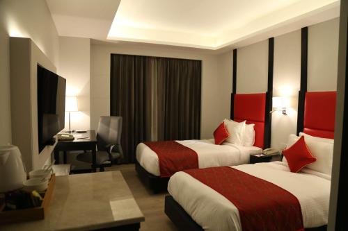 a hotel room with two beds and a television at Ramada Encore Jalandhar in Jalandhar