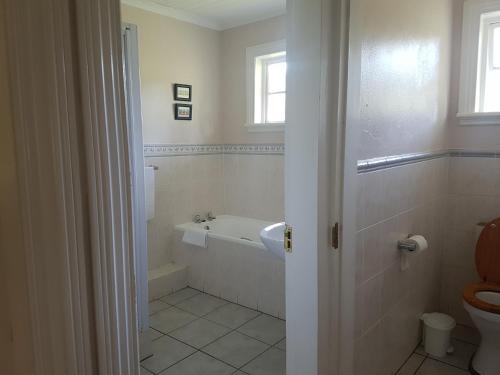 ein Badezimmer mit Badewanne, Toilette und Waschbecken in der Unterkunft Rosebury Cottage in Underberg