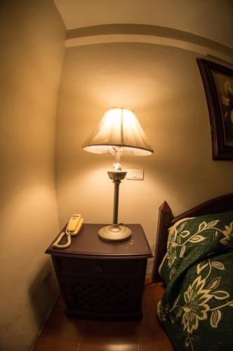 a lamp on a table next to a bed at Hotel posada casa regia in Xalapa
