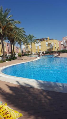 una gran piscina azul con palmeras y edificios en Vera Playa Laguna Beach Resort, en Vera