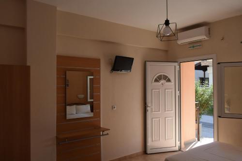 a bedroom with a bed and a tv and a door at Lafazanis rooms in Nea Vrasna