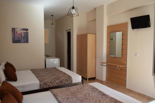 a small hotel room with two beds and a television at Lafazanis rooms in Nea Vrasna
