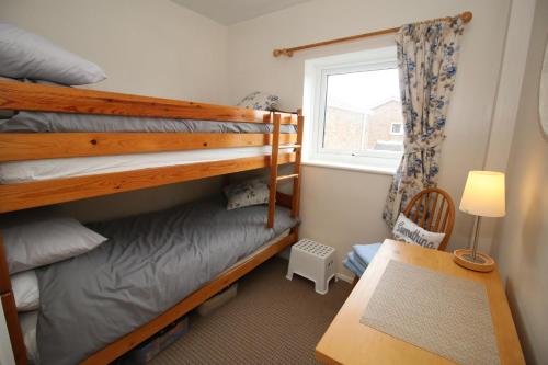 ein Schlafzimmer mit zwei Etagenbetten und einem Fenster in der Unterkunft Beadnell Cottage in Beadnell