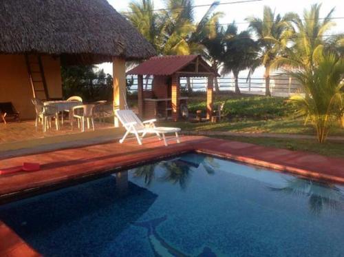a resort with a swimming pool with a table and chairs at Casa Pierre in Monterrico