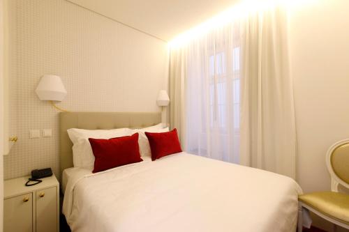 a bedroom with a white bed with red pillows at Hotel Lis Baixa in Lisbon